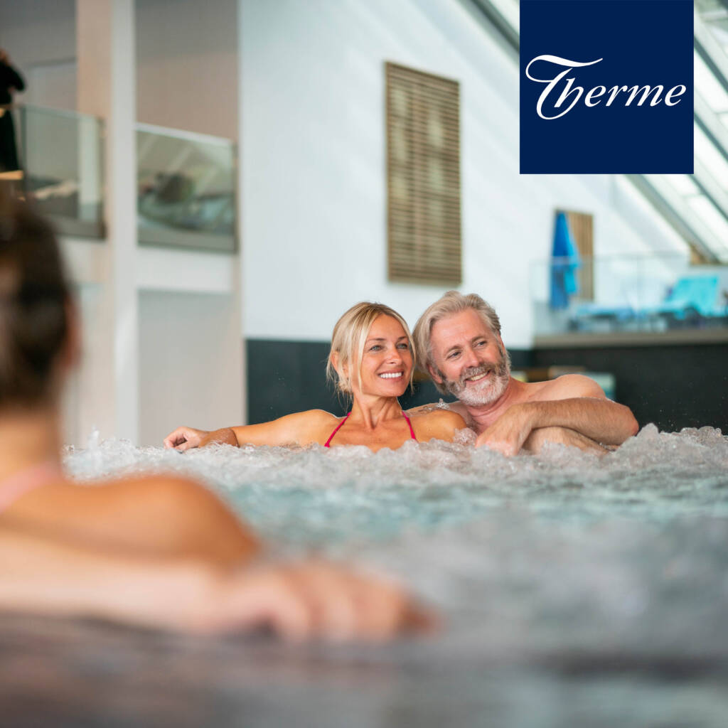 Glückliches Paar entspannt im Whirlpool im Innenbereich der Wohlfühl-Therme Bad Griesbach.